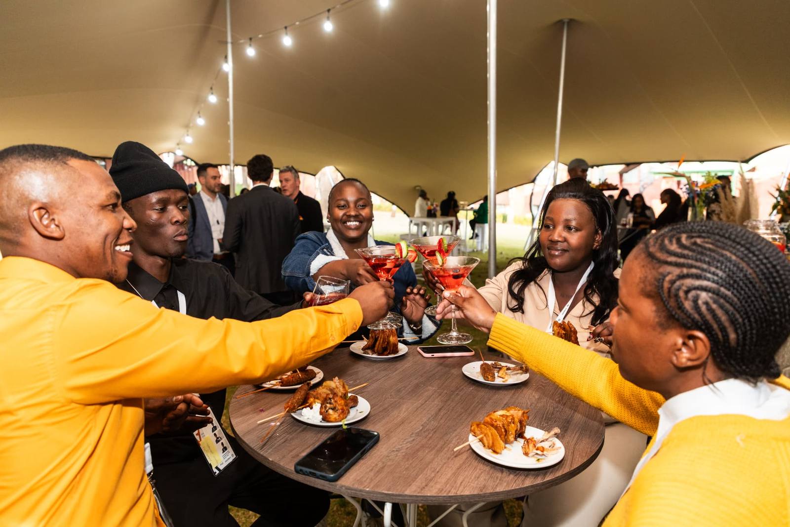Guests toasting cocktails under a stretch tent at an event