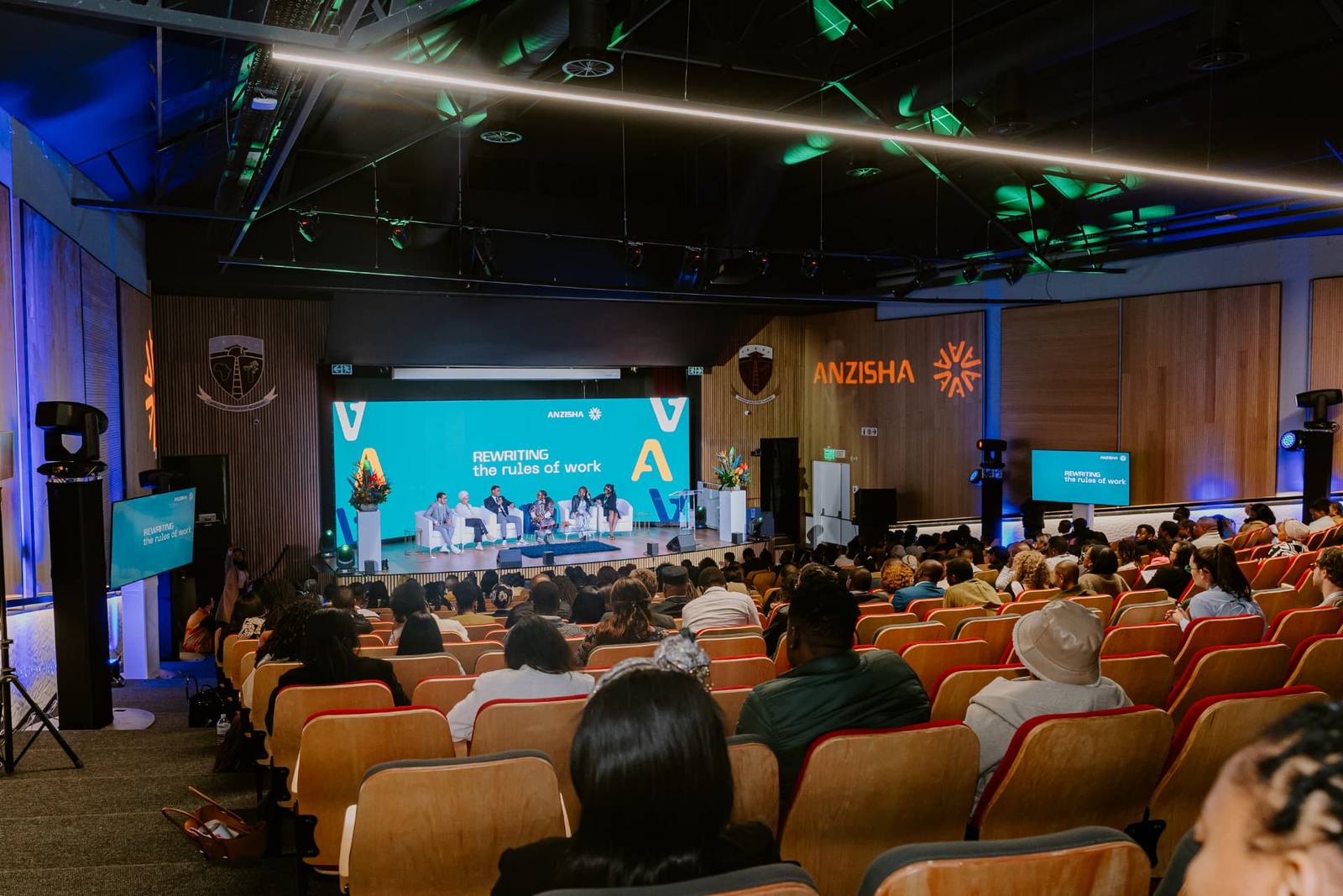 Panel discussion on stage in front of a full auditorium